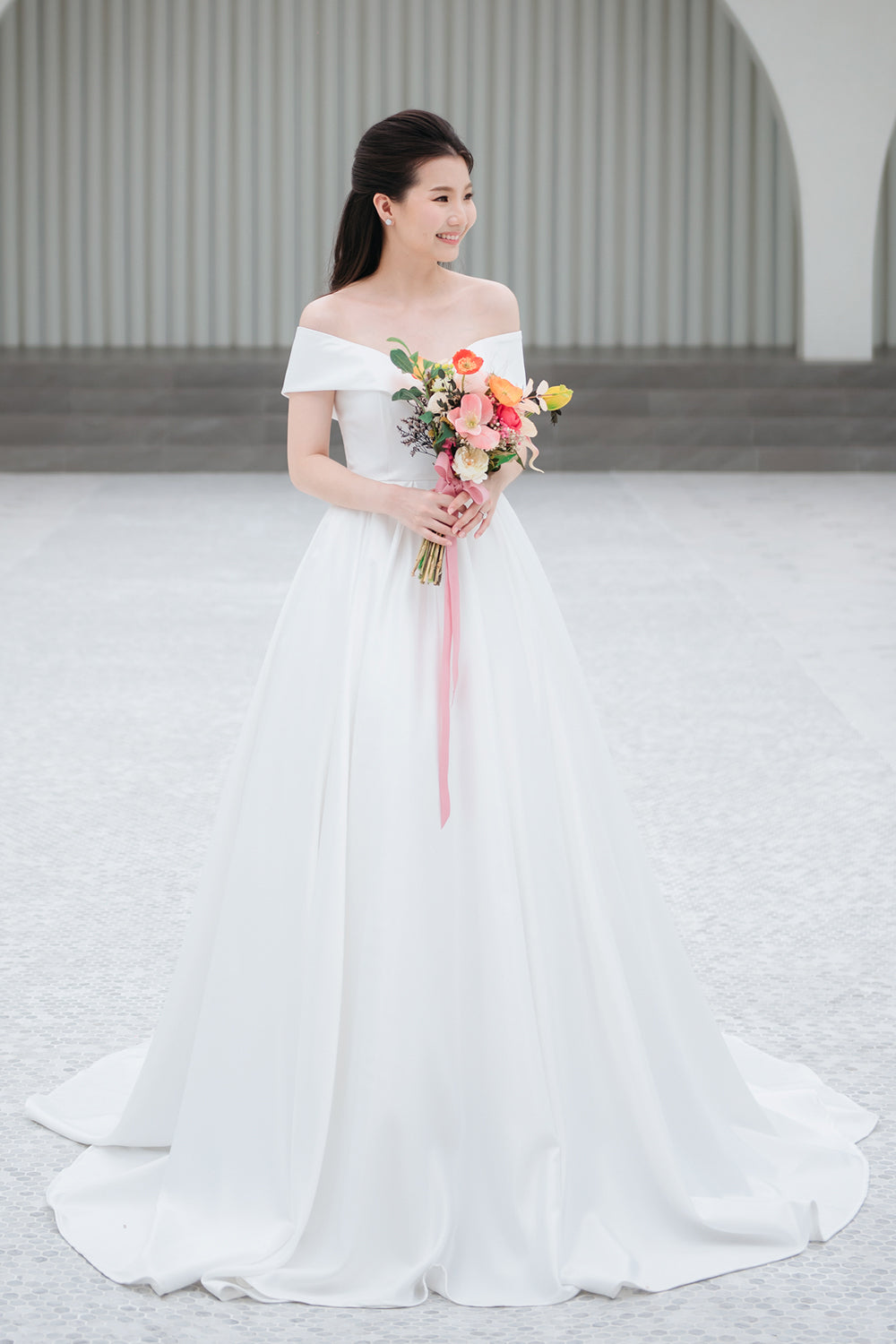 model wearing a white voluminous off-the-shoulder neckline wedding gown