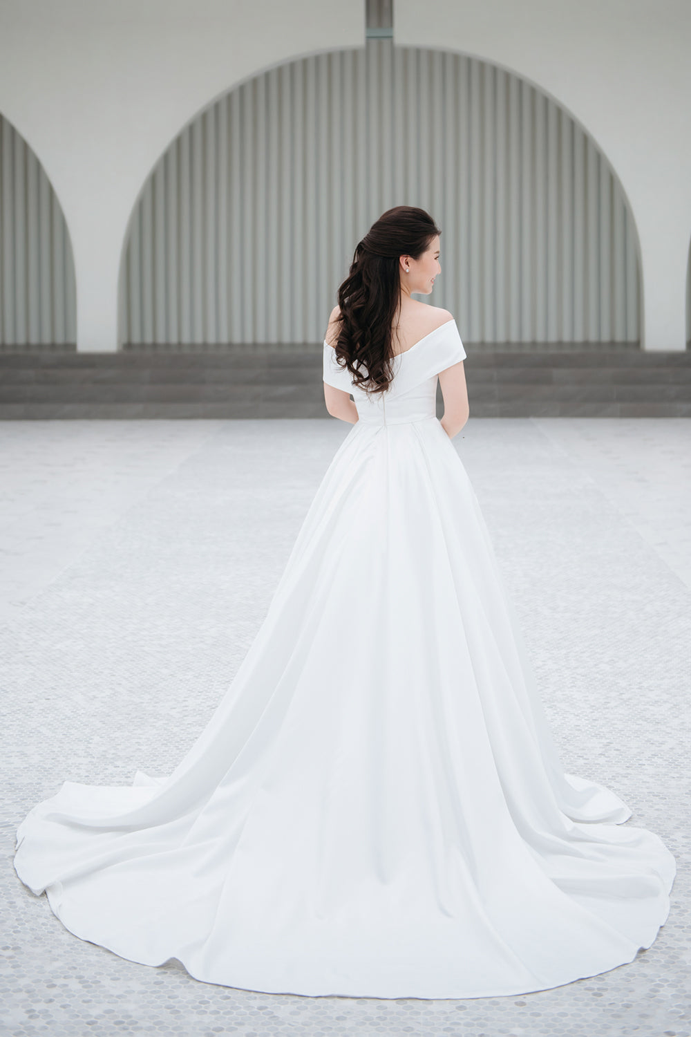 model wearing a white voluminous off-the-shoulder neckline wedding gown