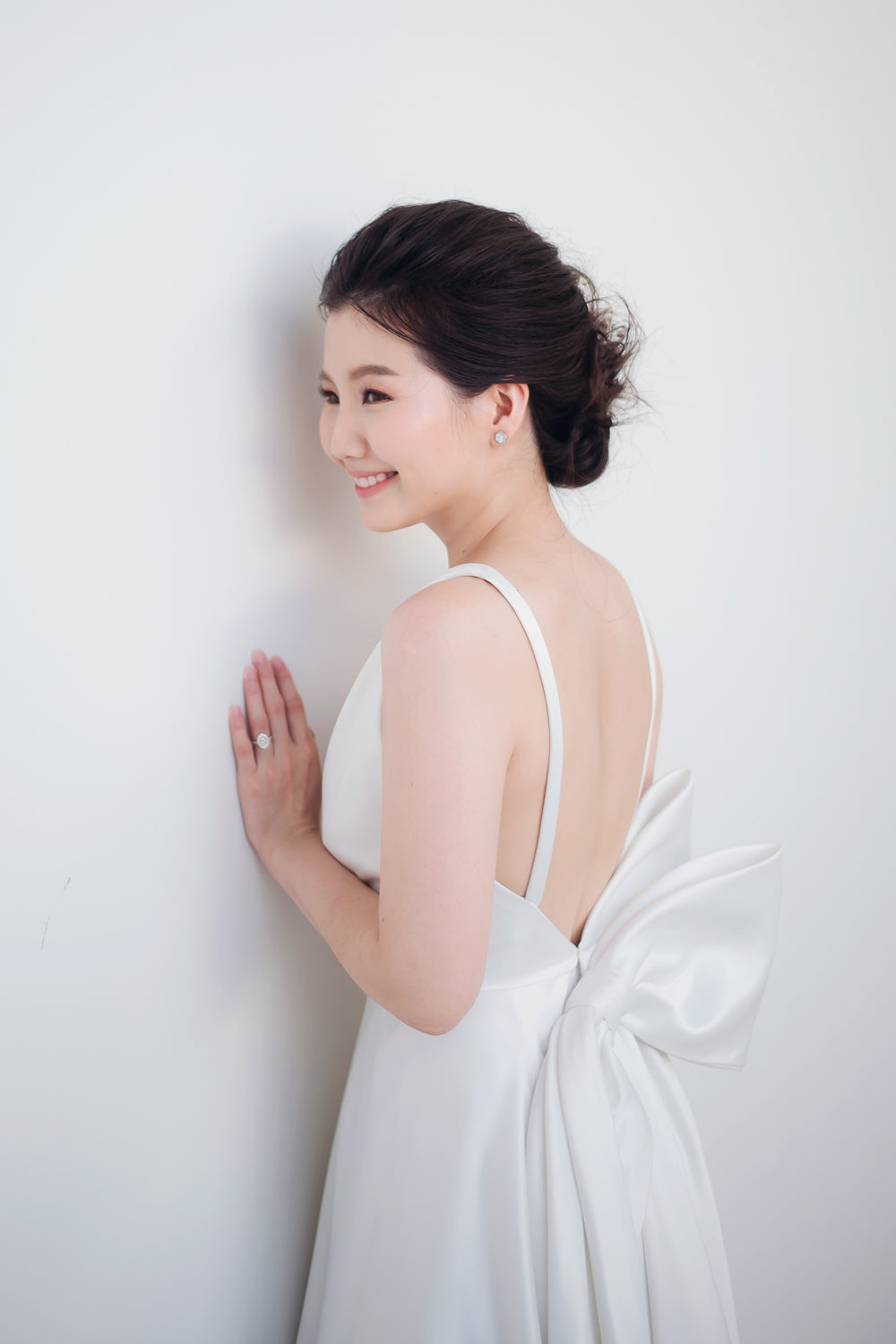 close up of a model wearing a white draped v neck minimal wedding gown 