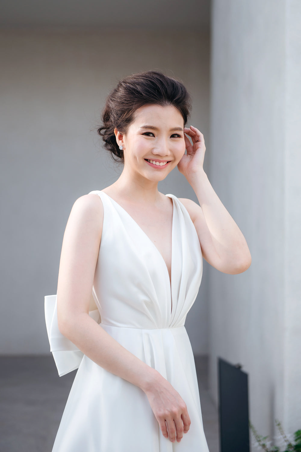 close up of a model wearing a white draped v neck minimal wedding gown 