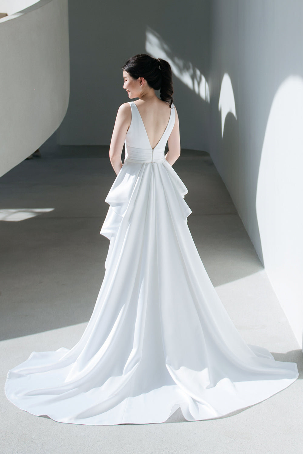 model wearing a white plunging v neck wedding gown with a detachable train