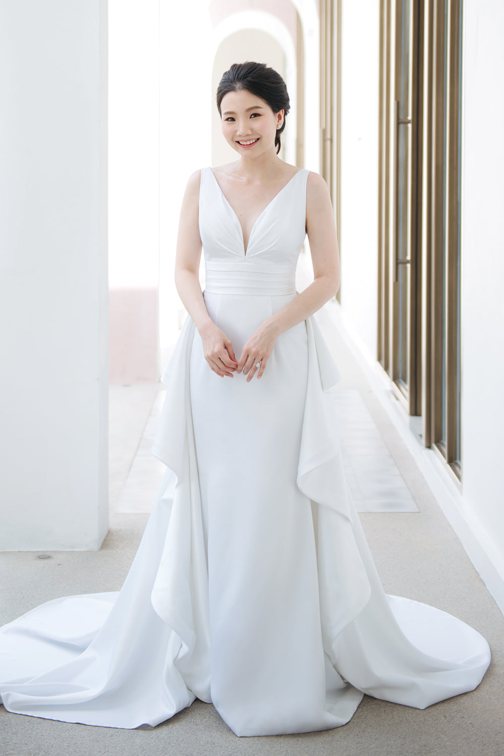 model wearing a white plunging v neck wedding gown with a detachable train