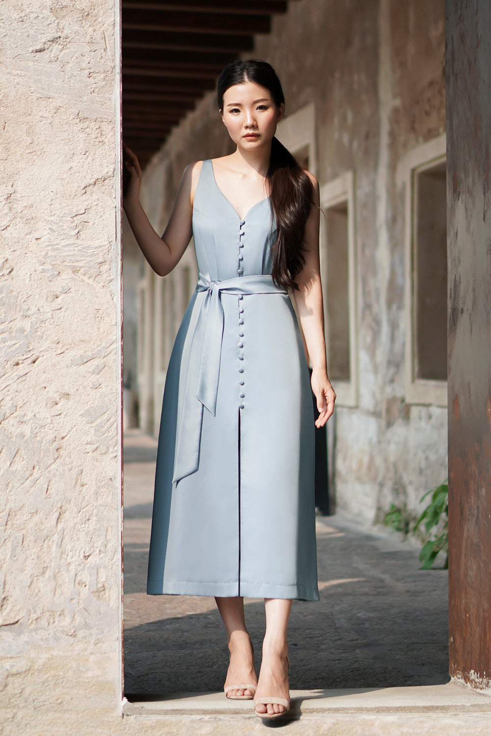 model wearing a frost blue casual sleeveless midi dress with dainty button detail