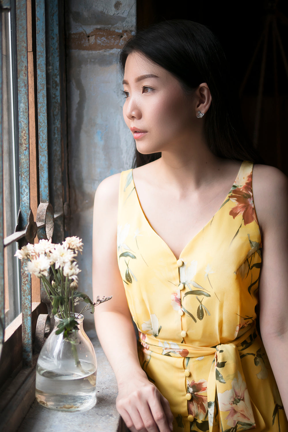 model wearing a yellow floral print casual v neck midi dress with dainty button detail