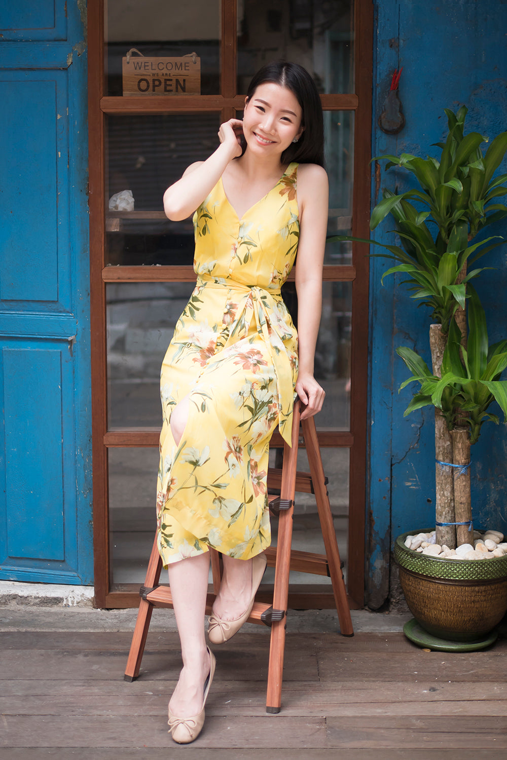 model wearing a yellow floral print casual v neck midi dress with dainty button detail