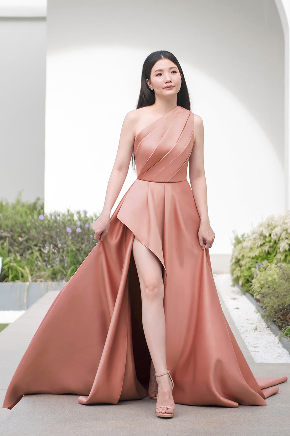 model wearing a one-shoulder full flair circle skirt minimal wedding gown in rosy beige color