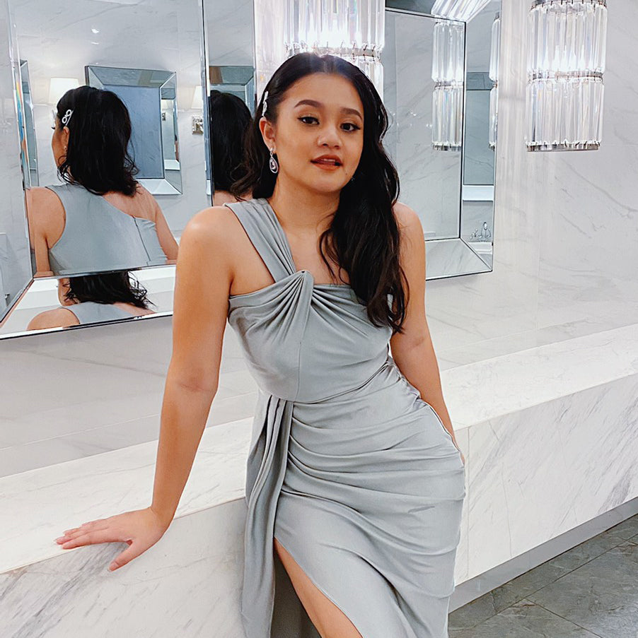 woman wearing a silver gray one shoulder wedding guest dress