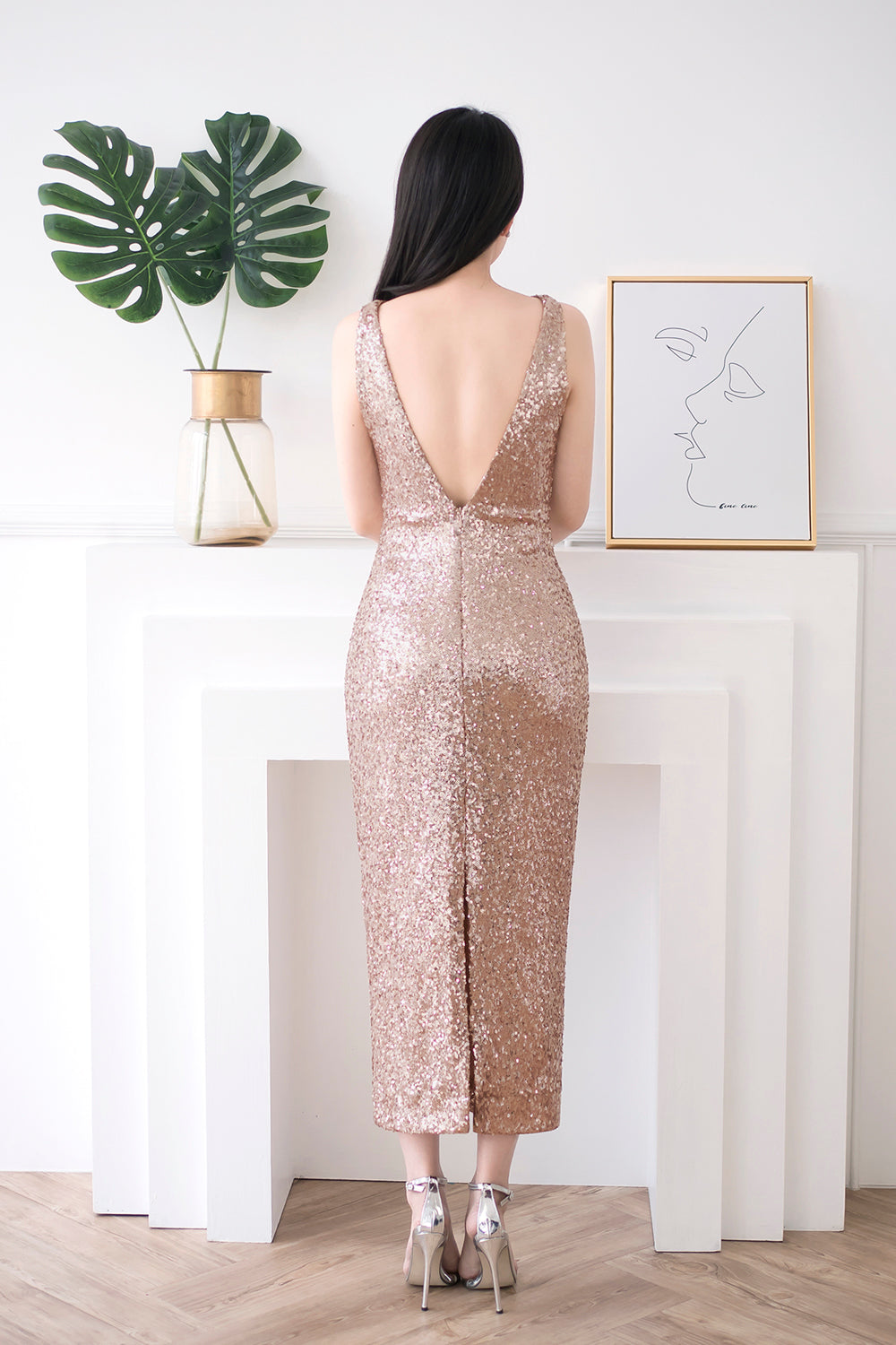 model wearing a glamorous midi open back rose gold sequin dress