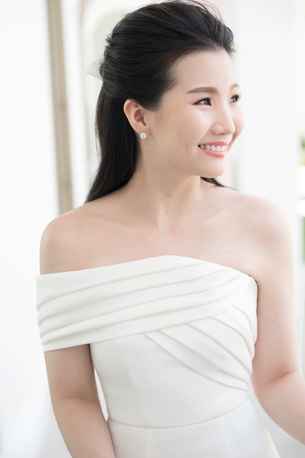 close up of model wearing a white one shoulder draped minimal wedding gown 