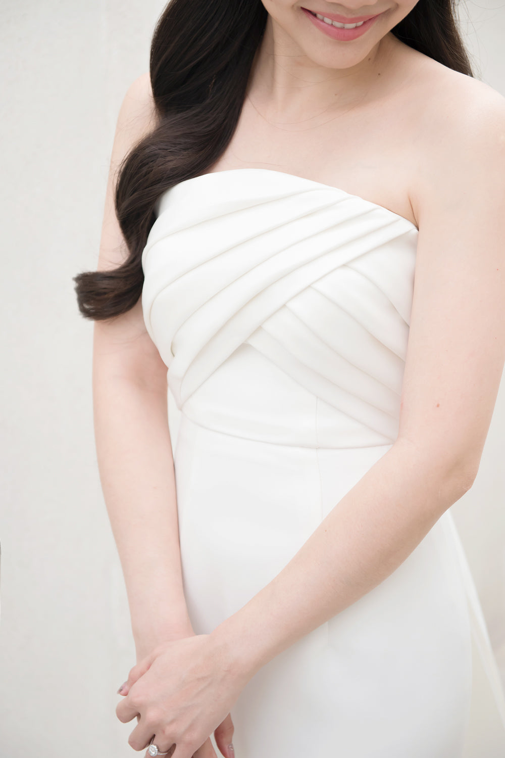 close up of a model wearing a white strapless draped minimal wedding gown