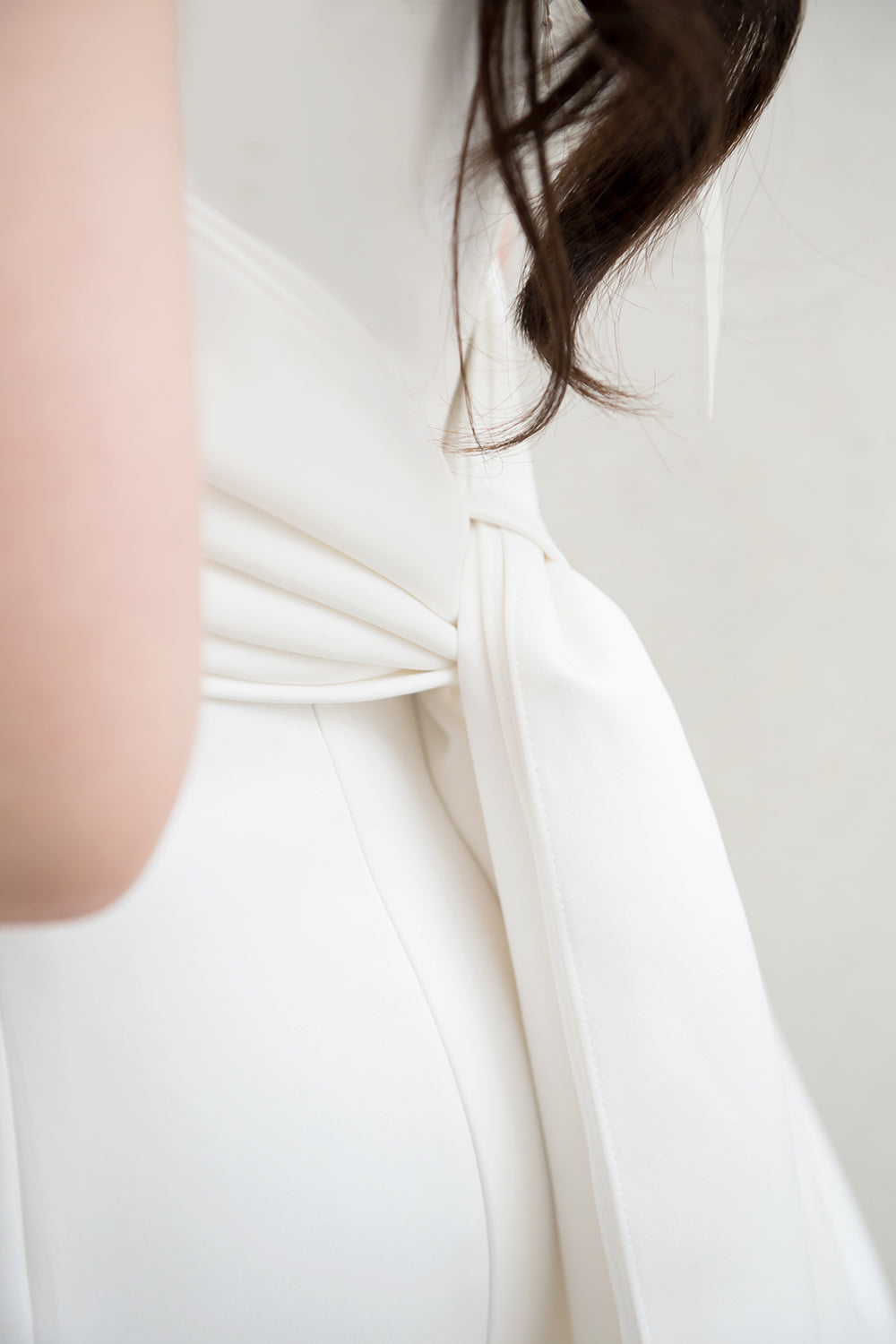 close up of a model wearing a white off the shoulder draped minimal wedding gown 