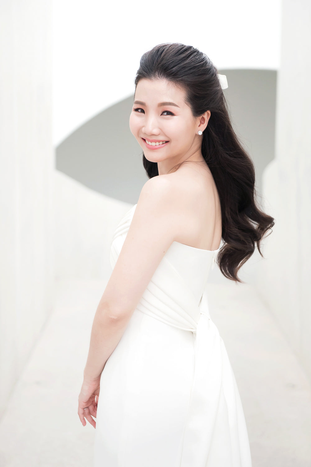 close up of a model wearing a white strapless draped minimal wedding gown 