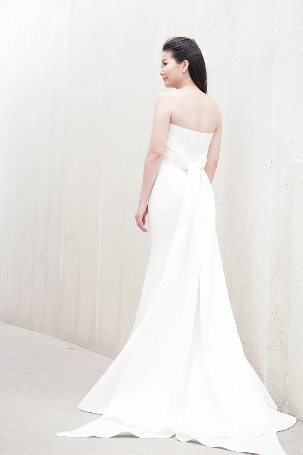 model wearing a white strapless draped minimal wedding gown 