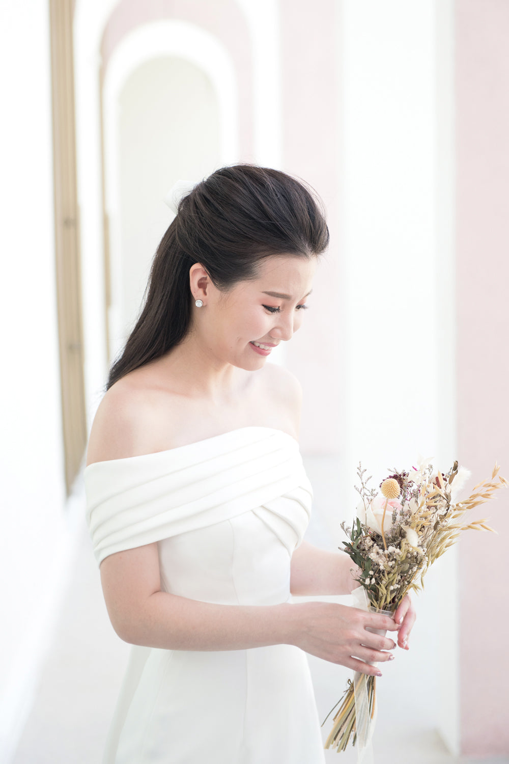 close up of model wearing a white one shoulder draped minimal wedding gown 