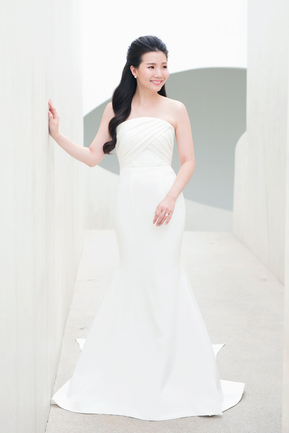 model wearing a white strapless draped minimal wedding gown 