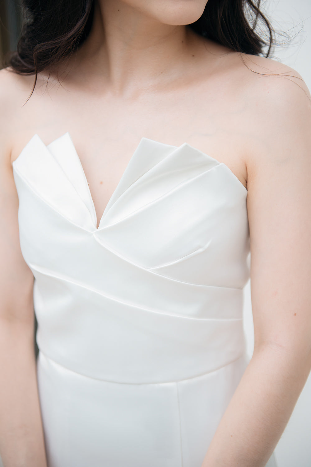 close up of a model wearing a white origami inspired strapless minimal wedding gown