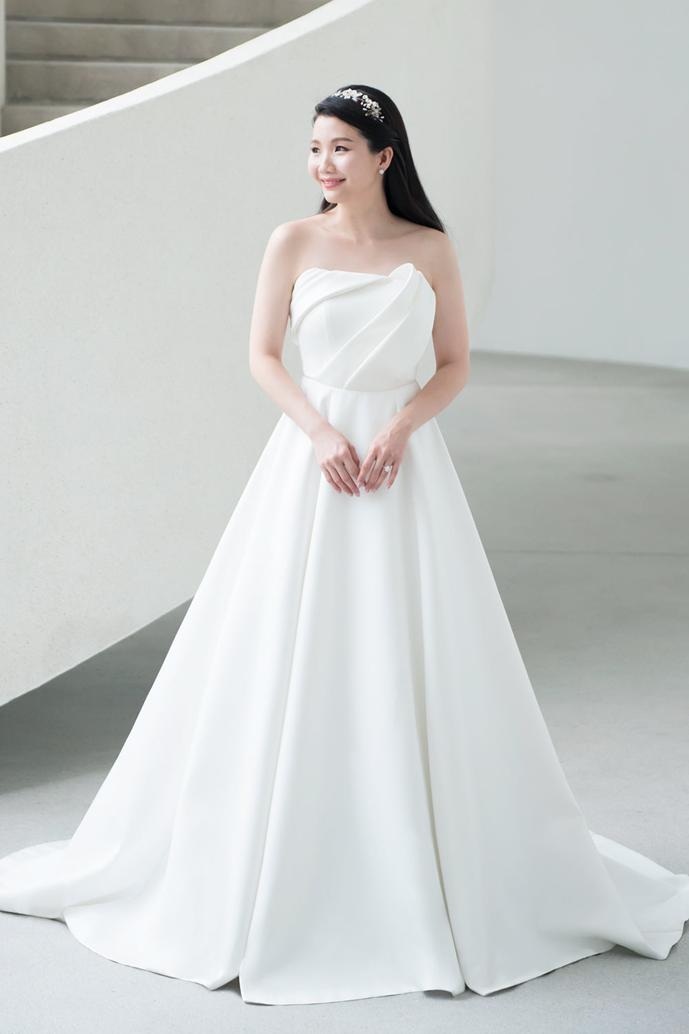 close up of a model wearing a white strapless minimal wedding gown with 3D bodice drape details