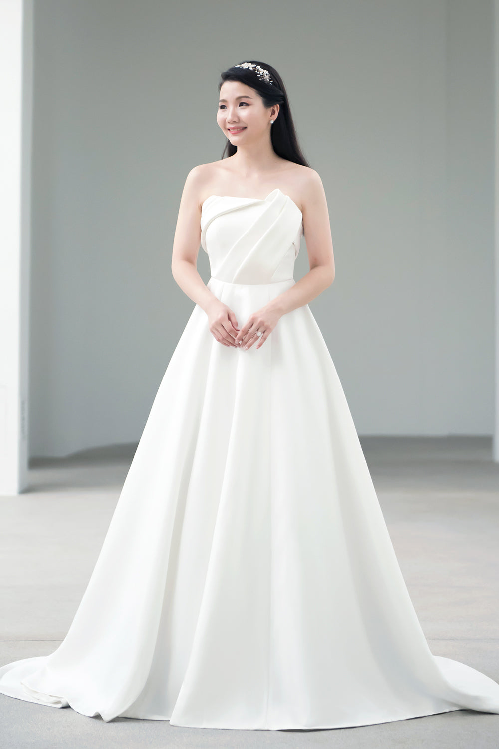 model wearing a white strapless minimal wedding gown with 3D bodice drape details