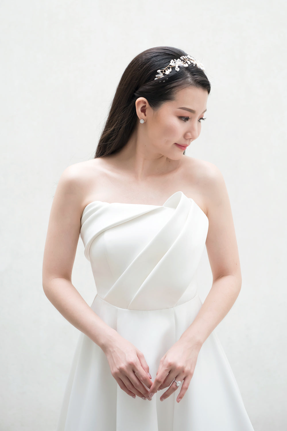 close up of a model wearing a white strapless minimal wedding gown with 3D bodice drape details