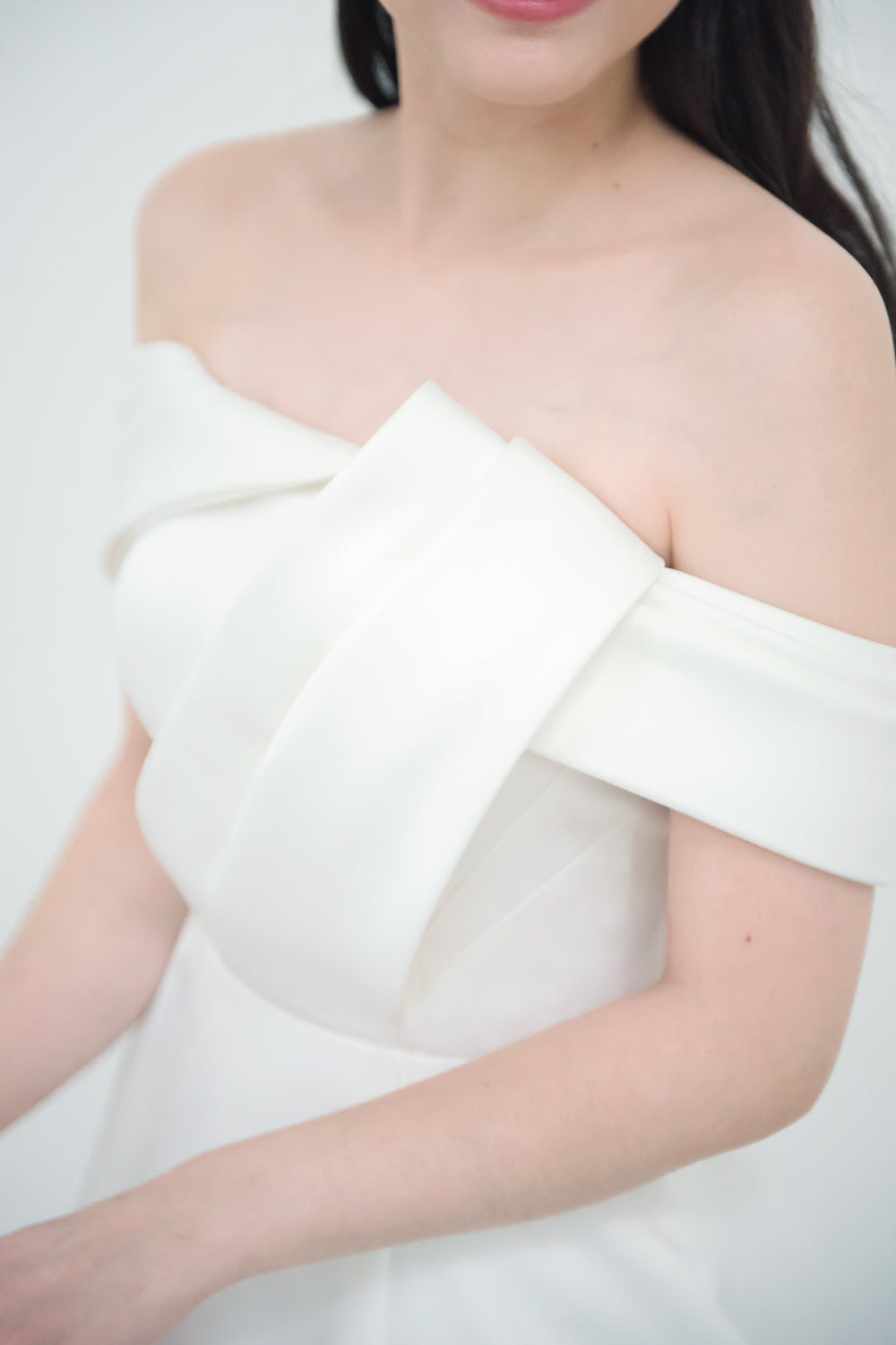 close up of a model wearing a white minimal wedding gown with 3D bodice drape details