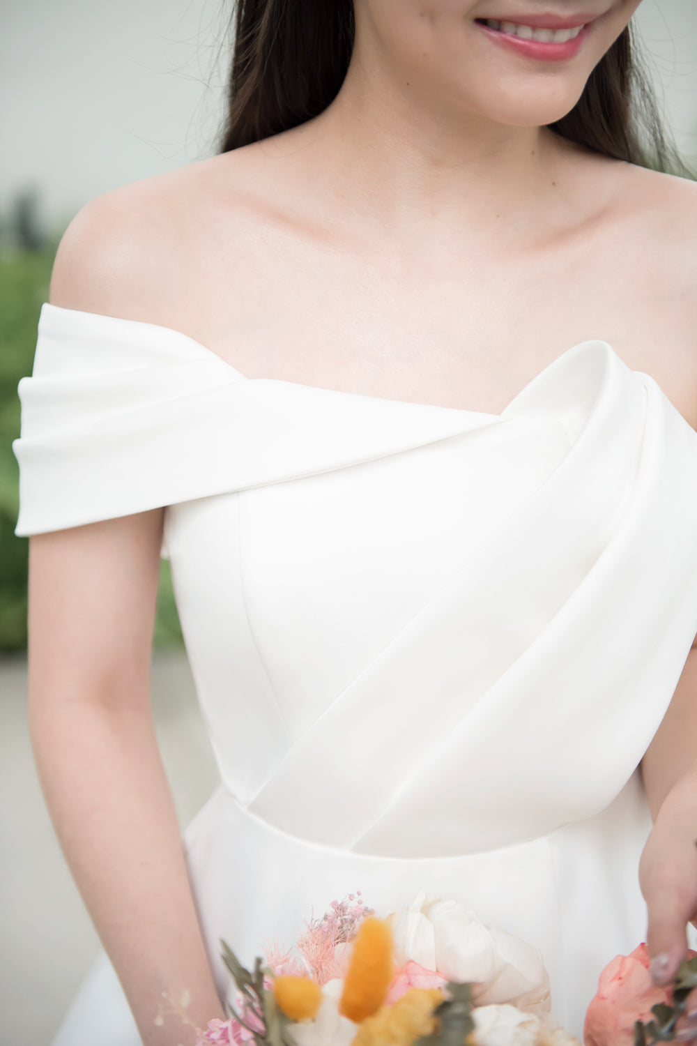 close up of a model wearing a white minimal wedding gown with 3D bodice drape details