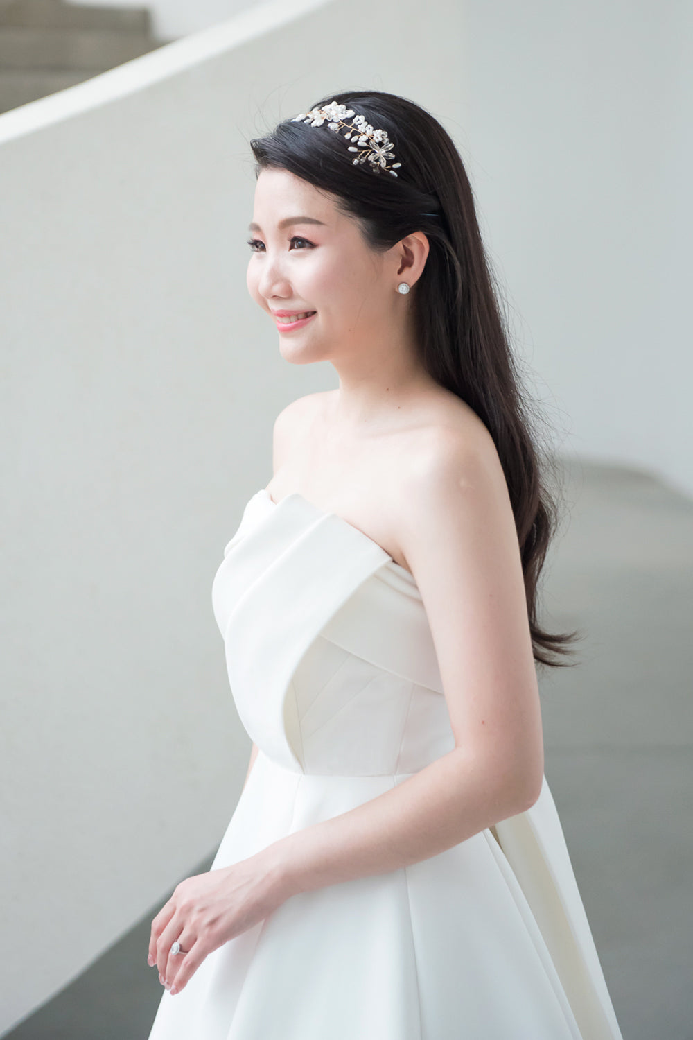 close up of a model wearing a white strapless minimal wedding gown with 3D bodice drape details