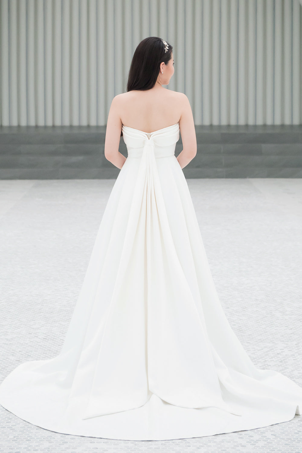 model wearing a white strapless minimal wedding gown with 3D bodice drape details